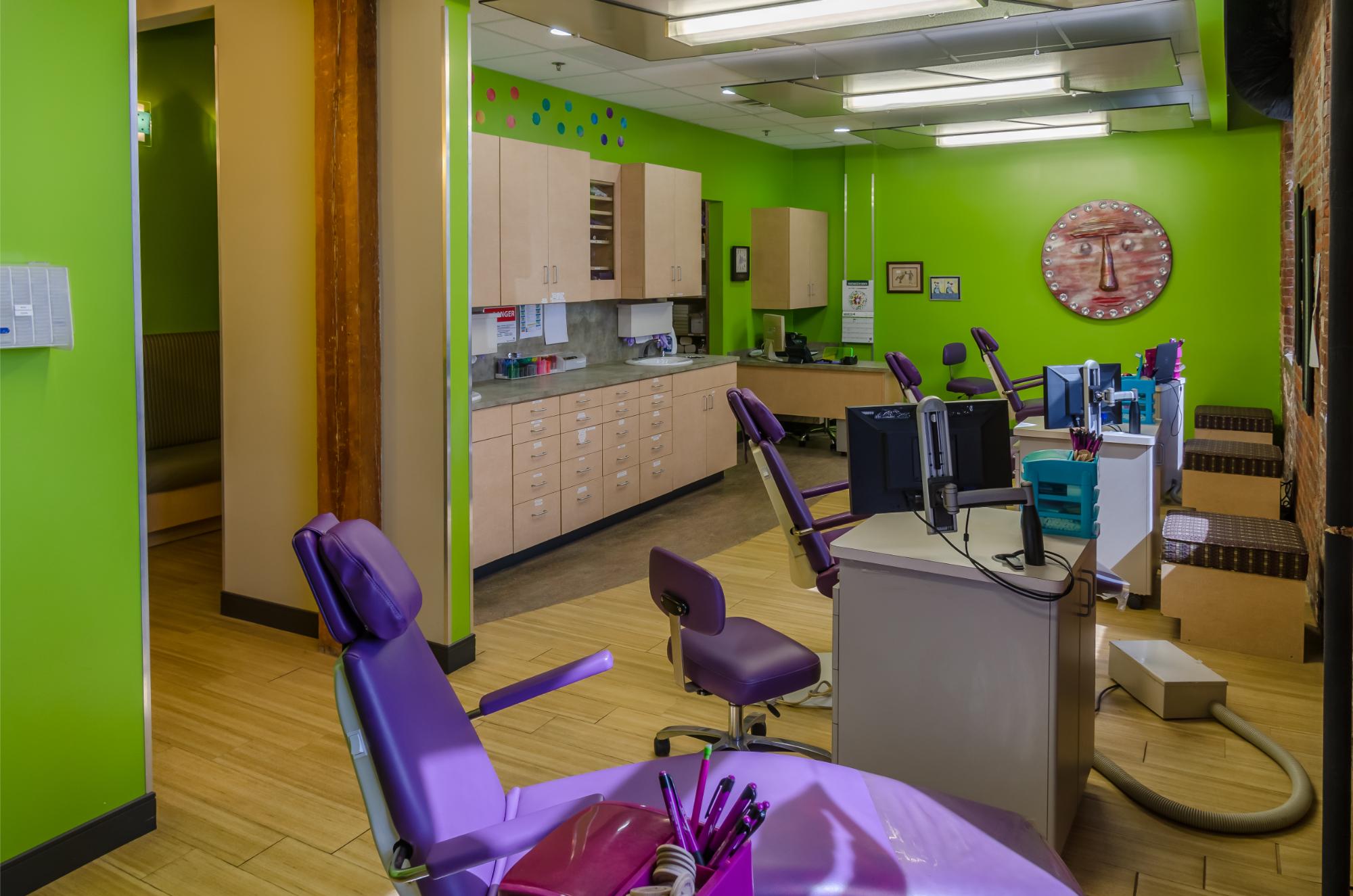 Orthodontic office interior at Braces by Dr. Ruth, featuring purple dental chairs, green walls, and orthodontic equipment, emphasizing a welcoming environment for patients in Brentwood and Nashville.